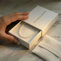 Thumbnail for Freshwater Pearl Choker by Brother & Sisters nestled in elegant packaging with a hand holding the box.