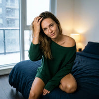 Thumbnail for Woman in a green cashmere jumper wearing the rose gold Crystal Bar Bracelet, snow at the window