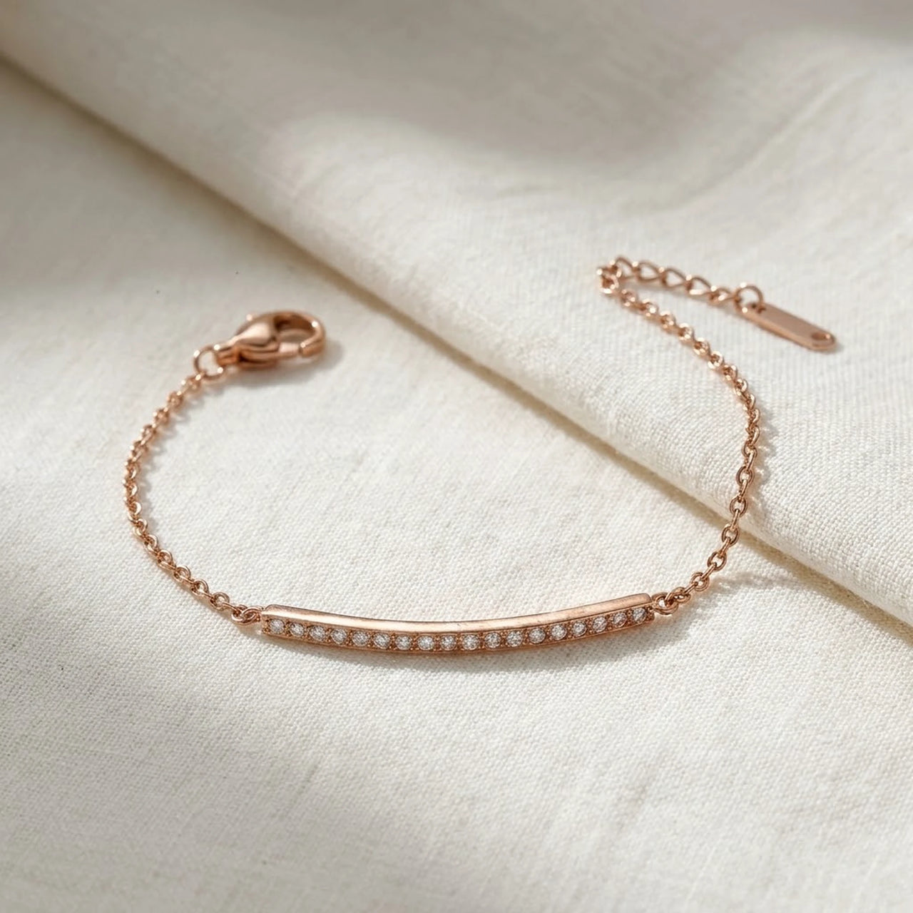 Crystal Bar Bracelet in rose gold stainless steel, crystal-set bar, laid flat on linen