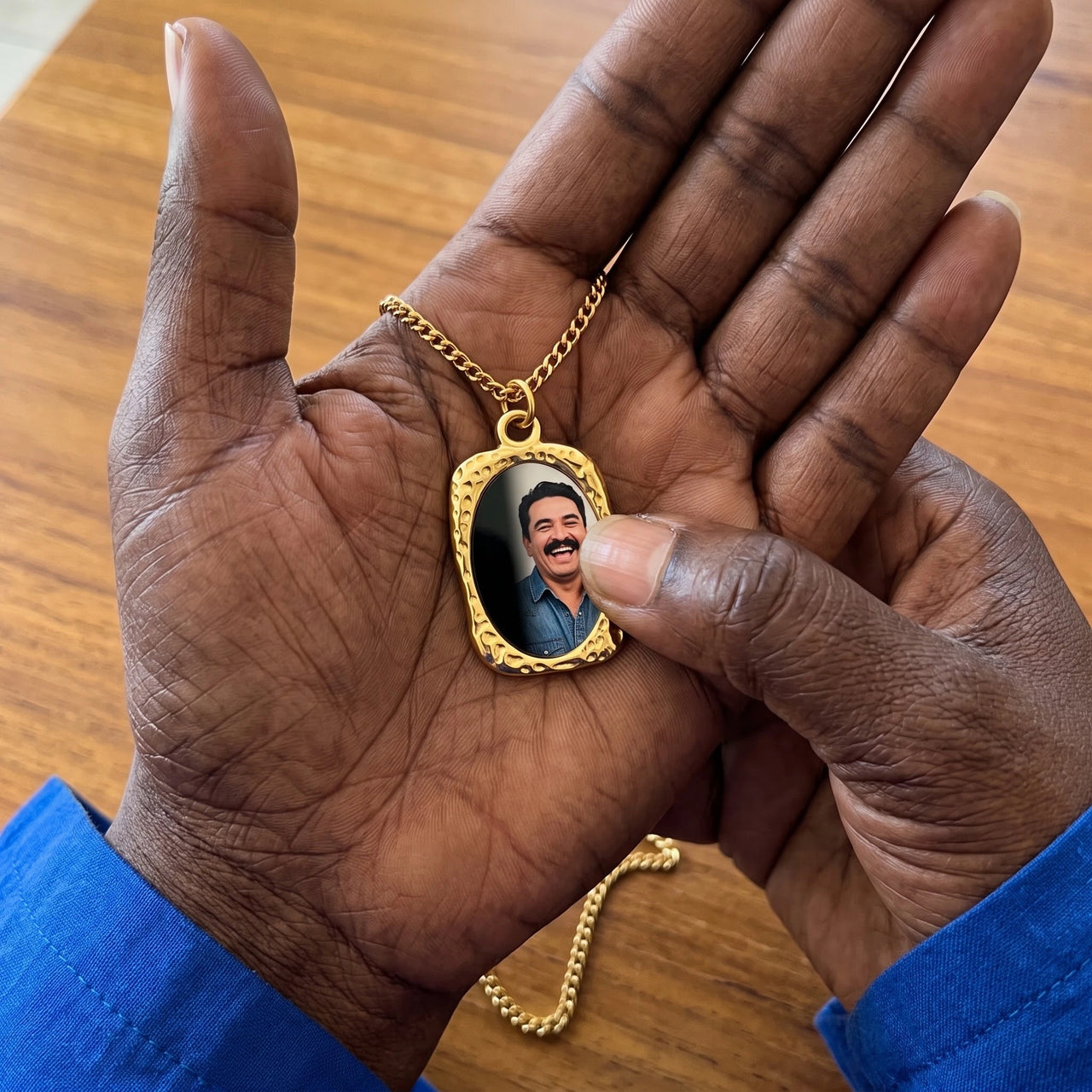 Thumb warming the gold oval pendant: the hidden photo appears under the thumb while the rest stays black | SKU: TPH-OVLN-GOLD