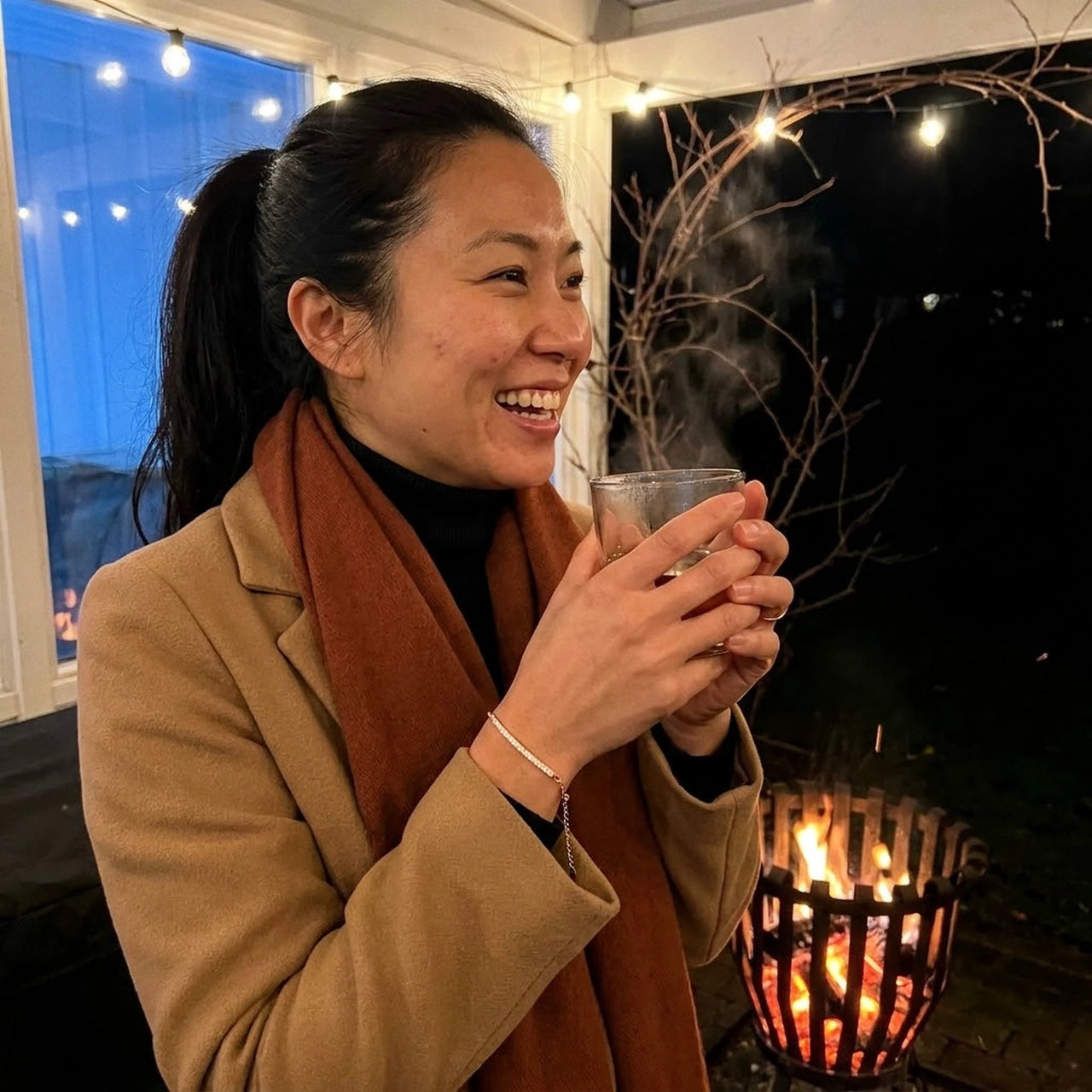 Woman wearing the rose gold Crystal Bar Bracelet on a winter terrace beside a fire basket